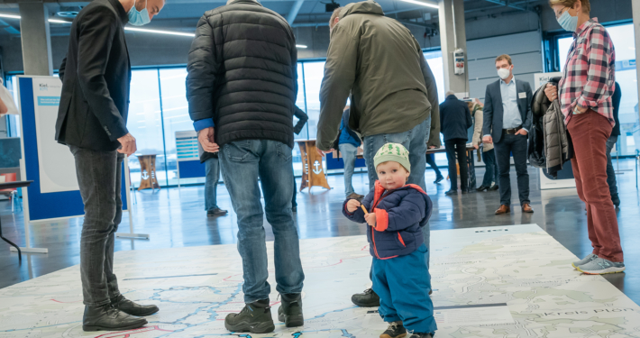 Besucher*innen des Bürger*innenforums betrachten eine riesige Karte mit dem Streckennetz von Kiel