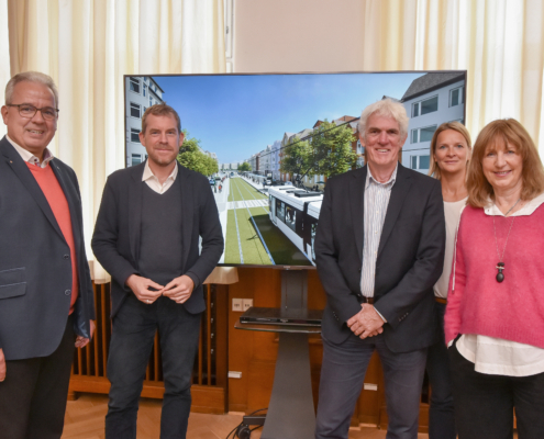 Oberbürgermeister Ulf Kämpfer steht gemeinsam mit mit Vertreter*innen von Kersig Immobilien, dem Verein "die holtenauer" vor einem Bildschirm, der das neue ÖPNV-System zeigt