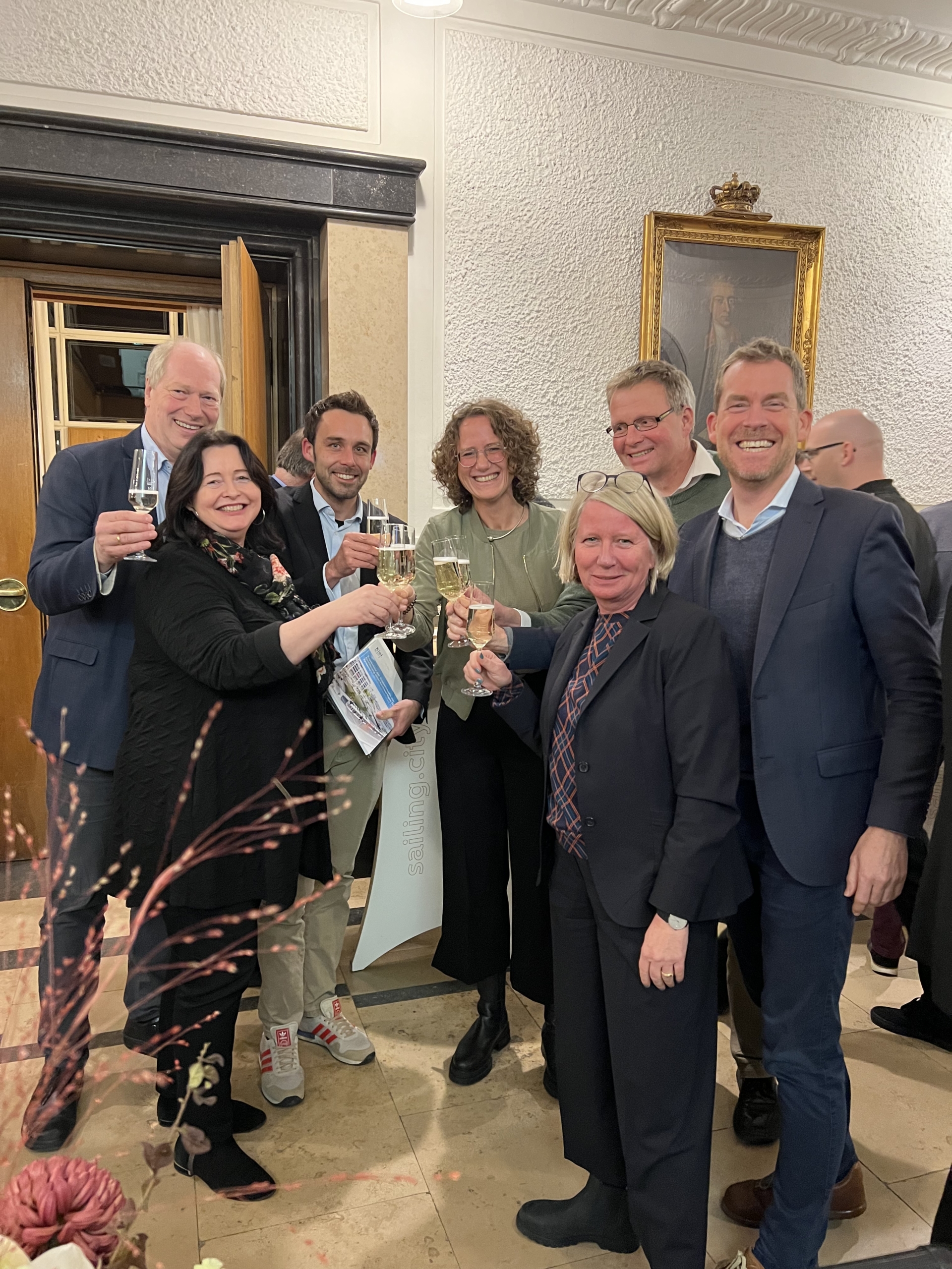 Mitglieder der Kieler Ratsversammlung stoßen voller Freude mit Sekt an